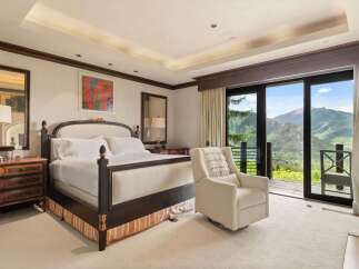 Experience luxury mountain living in this exquisite bedroom, featuring a plush king-size bed and a comfortable recliner perfect for enjoying the breathtaking panoramic views.