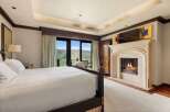 Experience luxury mountain living in this exquisite bedroom, featuring a cozy fireplace and breathtaking panoramic views of the surrounding peaks.