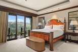 Experience luxury mountain living in this stunning bedroom featuring a grand wooden bed and a plush leather ottoman.