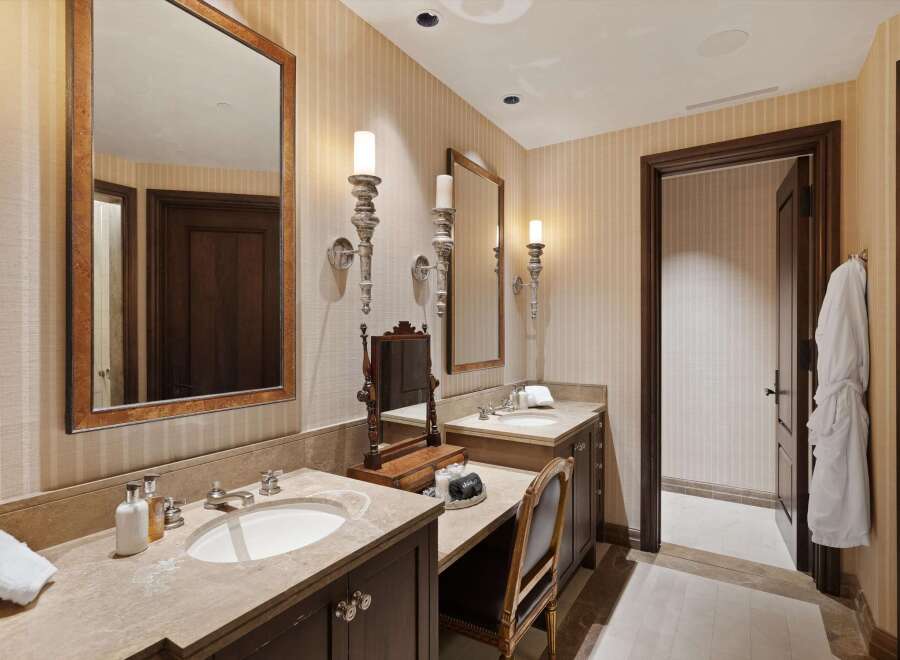 Experience luxury in this elegant bathroom featuring dual vanities with marble countertops and undermount sinks.