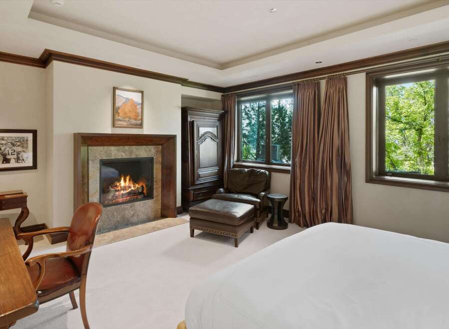 Experience ultimate comfort in this luxurious bedroom, featuring a cozy fireplace perfect for chilly evenings.