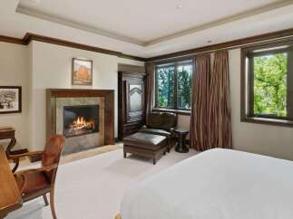 Experience ultimate comfort in this luxurious bedroom, featuring a cozy fireplace perfect for chilly evenings.