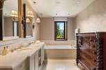 Indulge in luxury with this stunning bathroom featuring a spacious double vanity with marble countertops and elegant sconce lighting.