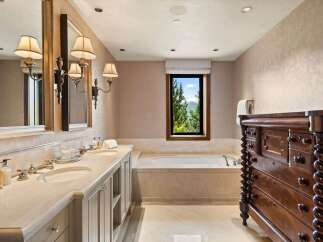 Indulge in luxury with this stunning bathroom featuring a spacious double vanity with marble countertops and elegant sconce lighting.
