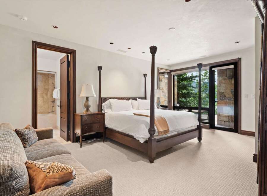 Experience luxury mountain living in this stunning bedroom featuring a grand four-poster bed and a comfortable seating area.
