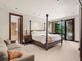 Experience luxury mountain living in this stunning bedroom featuring a grand four-poster bed and a comfortable seating area.