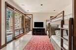 This spacious room features a modern entertainment area with a large flat-screen TV and a dark wood media console, complemented by a vibrant red and white patterned rug.