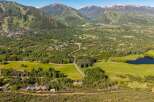 Experience luxury mountain living with this stunning aerial view of a sprawling estate nestled amidst lush greenery and majestic peaks.