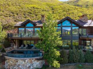 Experience luxury mountain living in this stunning estate, featuring expansive floor-to-ceiling windows that capture breathtaking panoramic views of snow-capped peaks and lush green hillsides.