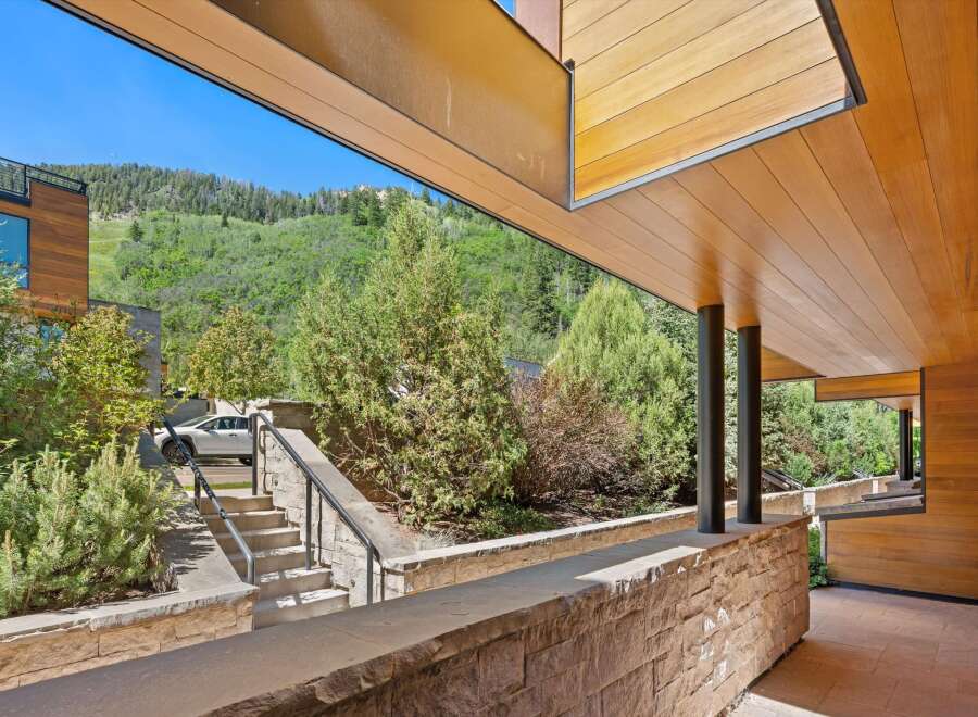 Experience modern luxury with this stunning property featuring a sleek wooden exterior and expansive windows that frame breathtaking mountain views.