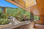 Experience modern luxury with this stunning property featuring a sleek wooden exterior and expansive windows that frame breathtaking mountain views.