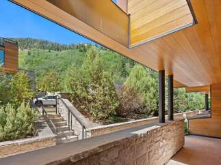 Experience modern luxury with this stunning property featuring a sleek wooden exterior and expansive windows that frame breathtaking mountain views.