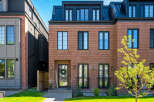 Discover modern urban living in this stunning brick townhouse, featuring a sleek black metal roof and expansive windows for abundant natural light.