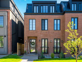Discover modern urban living in this stunning brick townhouse, featuring a sleek black metal roof and expansive windows for abundant natural light.