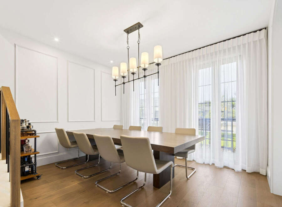 Experience elegant dining in this spacious room featuring a large wooden table and comfortable upholstered chairs, perfect for hosting gatherings.