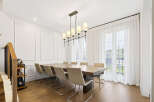 Experience elegant dining in this spacious room featuring a large wooden table and comfortable upholstered chairs, perfect for hosting gatherings.