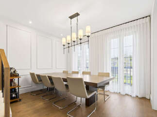 Experience elegant dining in this spacious room featuring a large wooden table and comfortable upholstered chairs, perfect for hosting gatherings.
