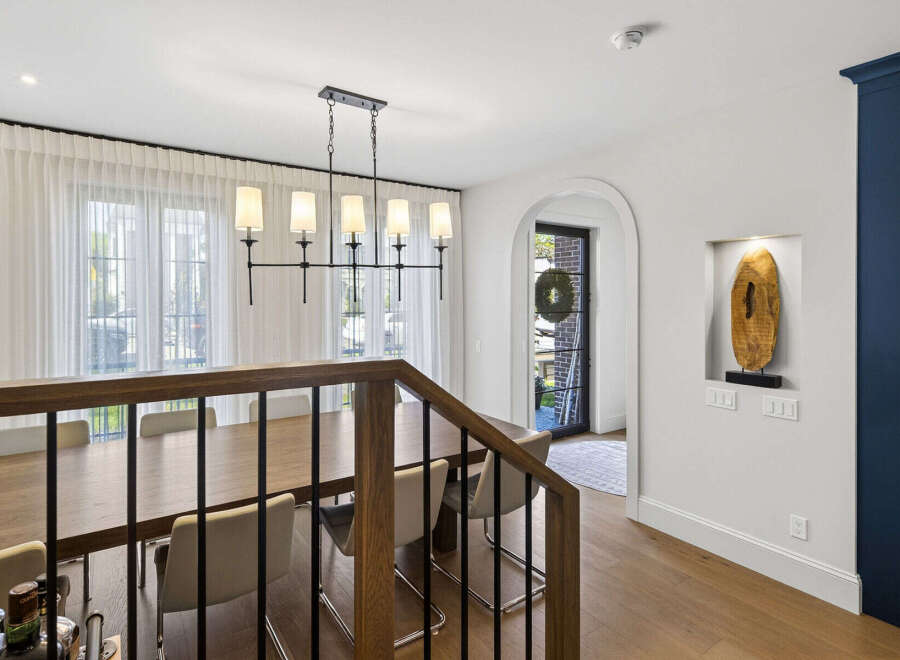 Experience elegant dining in this spacious room, featuring a large wooden table perfect for gatherings and illuminated by a stylish modern chandelier.