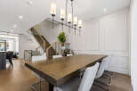 Experience elegant dining in this spacious home, featuring a large wooden dining table perfect for gatherings.