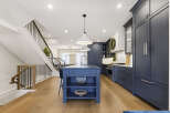 Experience luxury living in this stunning modern kitchen, featuring a spacious navy blue island with a waterfall countertop and sleek pendant lighting.