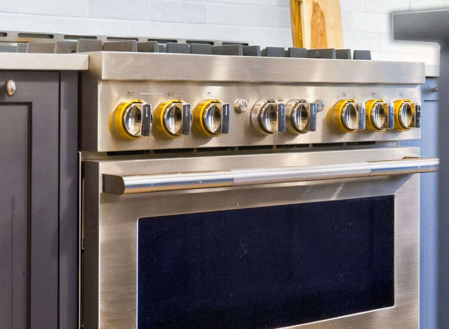 Experience culinary excellence with this professional-grade gas range, featuring a sleek stainless steel finish and striking yellow control knobs.