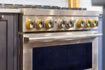 Experience culinary excellence with this professional-grade gas range, featuring a sleek stainless steel finish and striking yellow control knobs.