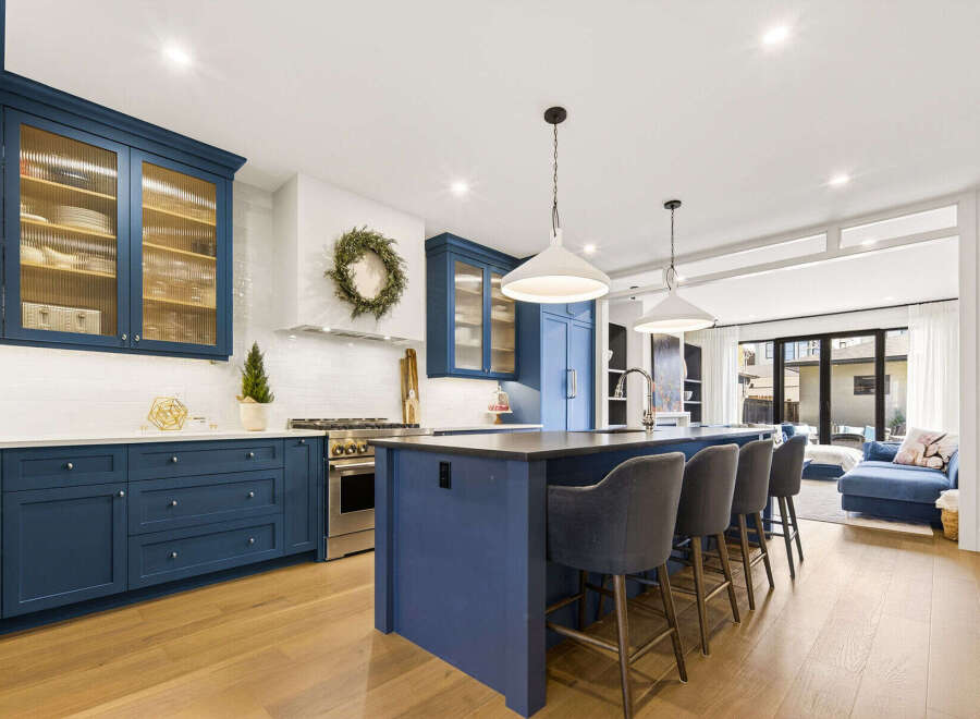 Experience luxury in this stunning kitchen featuring deep blue cabinetry and fluted glass upper cabinets.