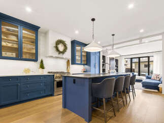 Experience luxury in this stunning kitchen featuring deep blue cabinetry and fluted glass upper cabinets.