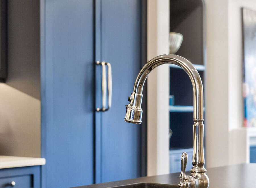 Experience luxury in this stunning kitchen featuring deep navy custom cabinetry and a sleek, modern faucet.