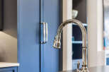Experience luxury in this stunning kitchen featuring deep navy custom cabinetry and a sleek, modern faucet.