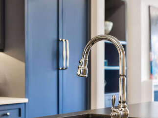 Experience luxury in this stunning kitchen featuring deep navy custom cabinetry and a sleek, modern faucet.