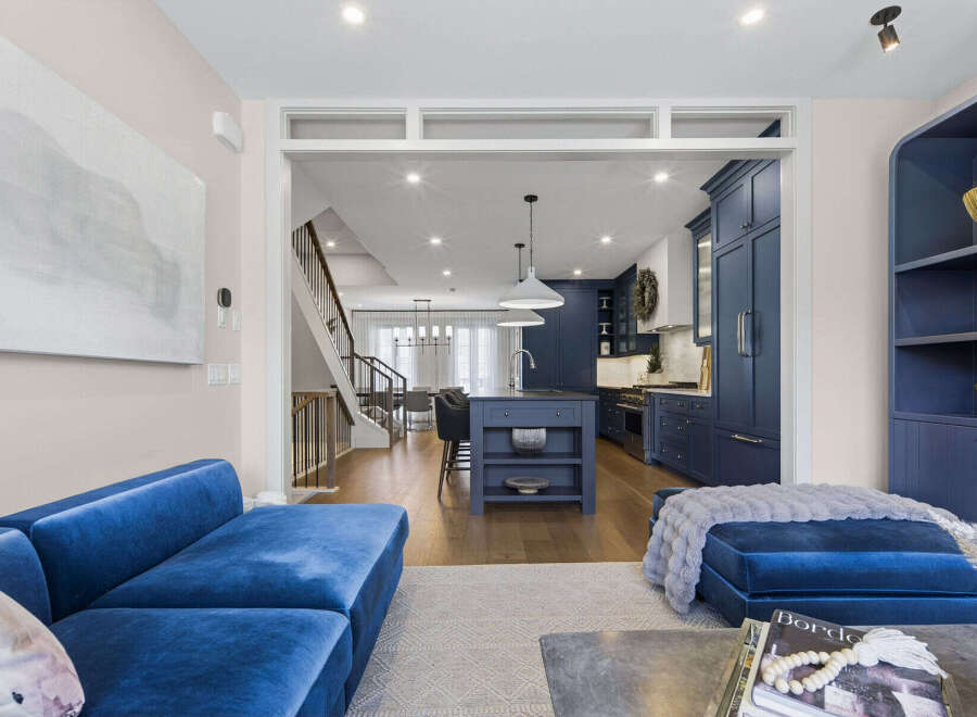 Experience modern luxury in this stunning open-concept living space, featuring a sleek navy blue kitchen with a central island and ample cabinetry.