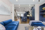 Experience modern luxury in this stunning open-concept living space, featuring a sleek navy blue kitchen with a central island and ample cabinetry.