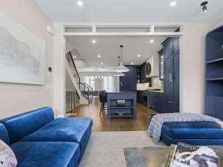 Experience modern luxury in this stunning open-concept living space, featuring a sleek navy blue kitchen with a central island and ample cabinetry.