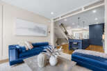 Experience modern luxury in this stunning open-concept living space, featuring a vibrant blue velvet sofa and a sleek concrete coffee table.