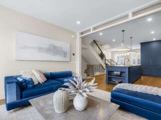 Experience modern luxury in this stunning open-concept living space, featuring a vibrant blue velvet sofa and a sleek concrete coffee table.