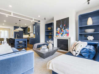 Experience modern luxury in this stunning open-concept living space, featuring a vibrant blue kitchen island and cabinetry that seamlessly flows into a chic living area.