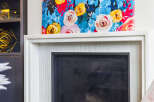 Elevate your living space with this stunning fireplace, featuring a vibrant floral artwork above and a sleek, modern design.