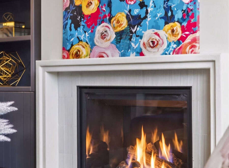 Cozy up by the modern gas fireplace, featuring a sleek white surround and a vibrant floral art piece above.