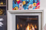 Cozy up by the modern gas fireplace, featuring a sleek white surround and a vibrant floral art piece above.