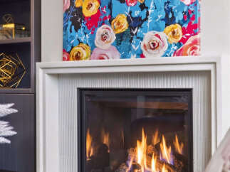 Cozy up by the modern gas fireplace, featuring a sleek white surround and a vibrant floral art piece above.