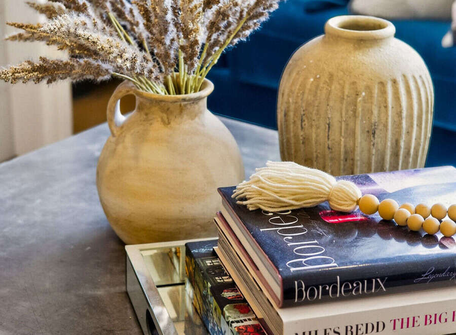 Elevate your living space with this stylish coffee table vignette, featuring a rustic ceramic vase filled with dried pampas grass and a stack of decorative books.