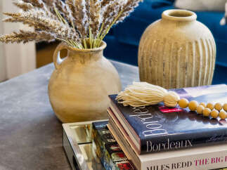 Elevate your living space with this stylish coffee table vignette, featuring a rustic ceramic vase filled with dried pampas grass and a stack of decorative books.