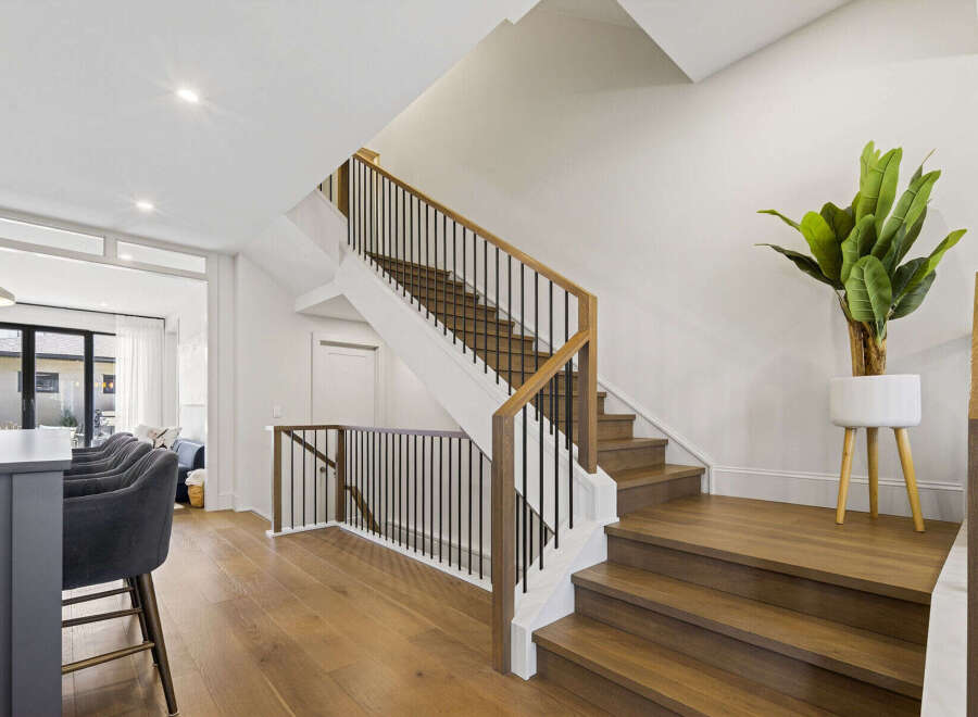 Experience modern living with this stunning staircase featuring rich hardwood treads and a sleek black metal railing.