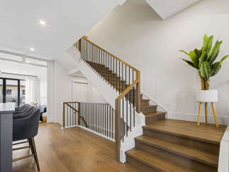 Experience modern living with this stunning staircase featuring rich hardwood treads and a sleek black metal railing.