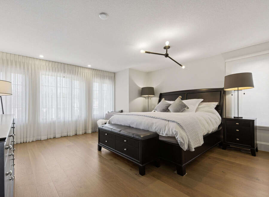 Experience ultimate comfort in this luxurious master bedroom, featuring a spacious king-size bed adorned with plush white linens and elegant throw pillows.