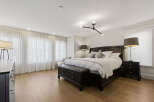 Experience ultimate comfort in this luxurious master bedroom, featuring a spacious king-size bed adorned with plush white linens and elegant throw pillows.