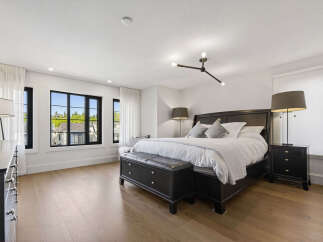 Experience luxury in this spacious master bedroom, featuring a king-sized bed with crisp white linens and plush pillows.