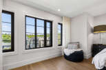 Experience luxury living in this beautifully appointed bedroom featuring expansive black-framed windows that offer picturesque views of the surrounding neighborhood.