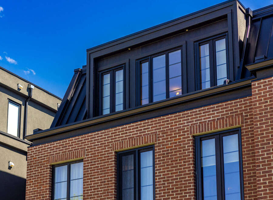 Experience modern urban living in this stunning multi-story residence featuring a striking brick facade and a sleek black metal roof.